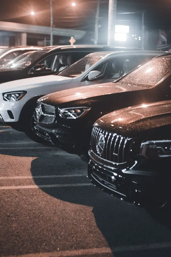 A row of premium used cars on a dealer lot at night.